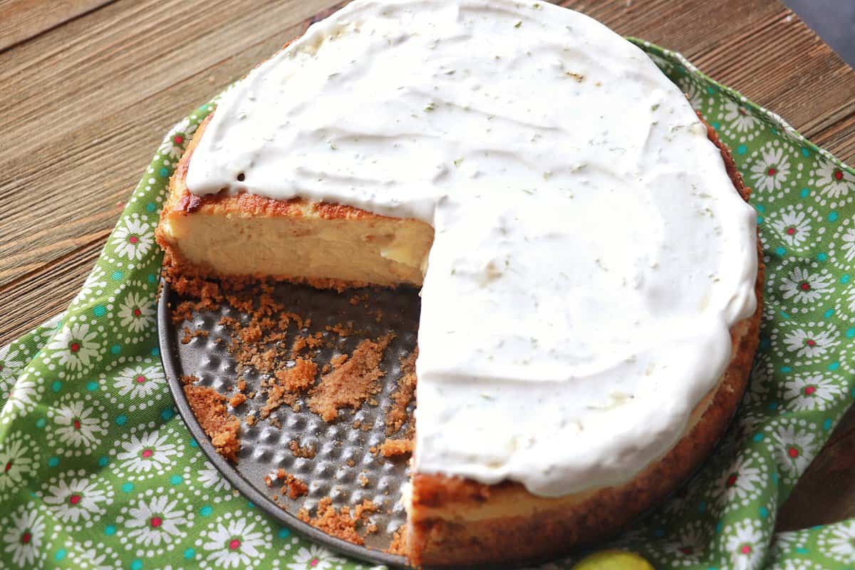 Key Lime Cheesecake on a spring form pan with a slice cut out.