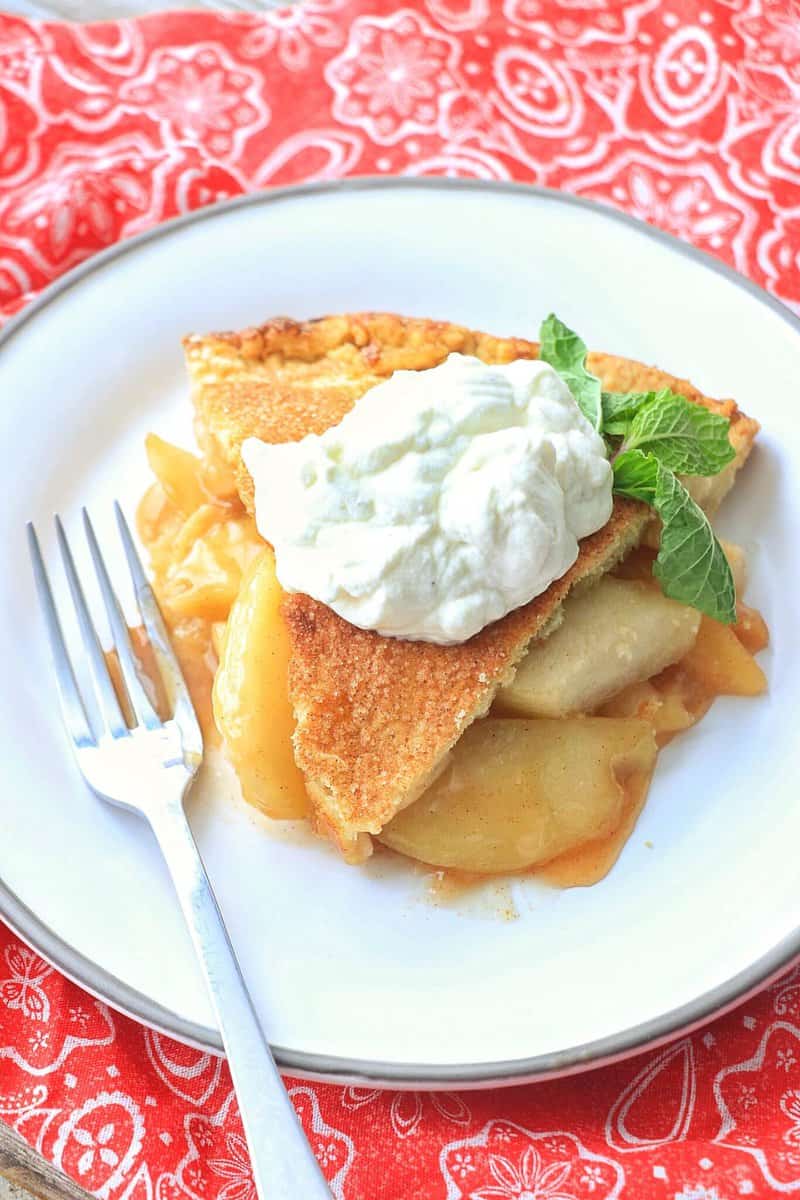 Classic Homemade Apple Pie on a plate with whipped cream.