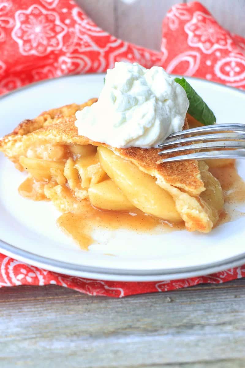 Classic Homemade Apple Pie on a plate with whipped cream.