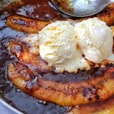 Bananas Foster in a skillet with vanilla ice cream