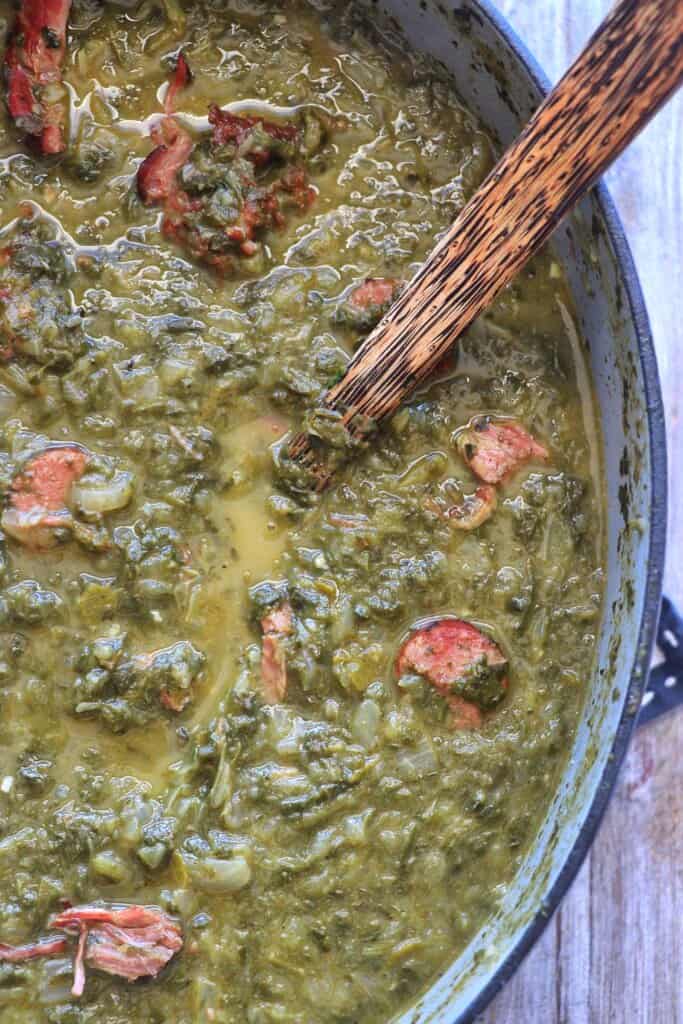 Close up overhead view of Gumbo Z'herbes in and pot with a wooden spoon