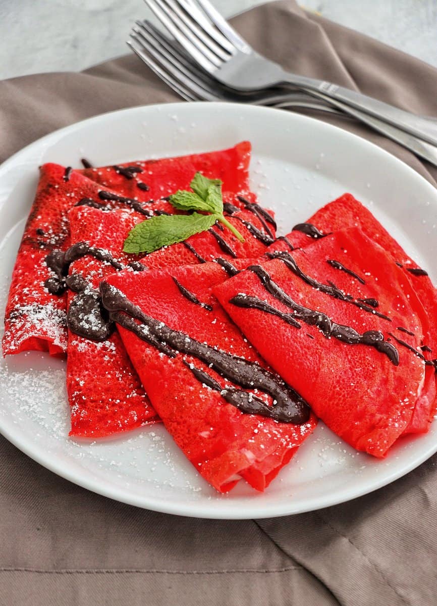 Close Up Picture of Red Velvet Crepe drizzled with chocolate syrup.