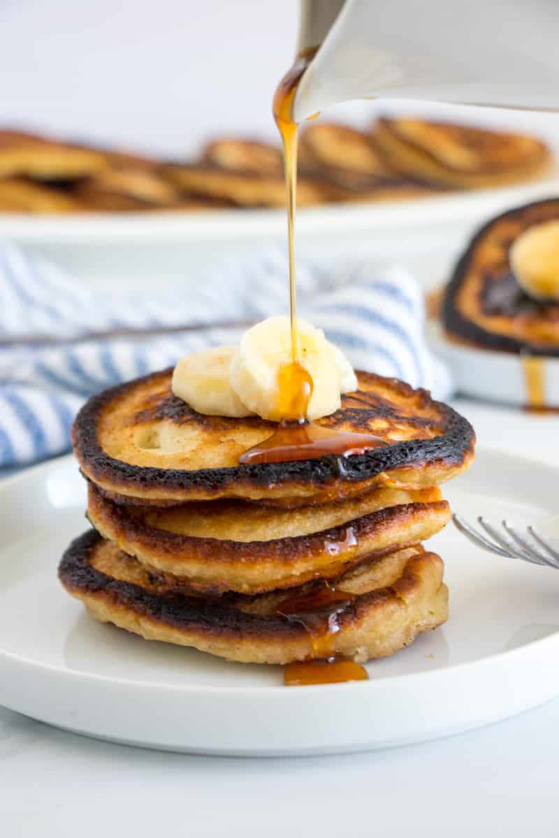 Syrup being poured over banana pancakes