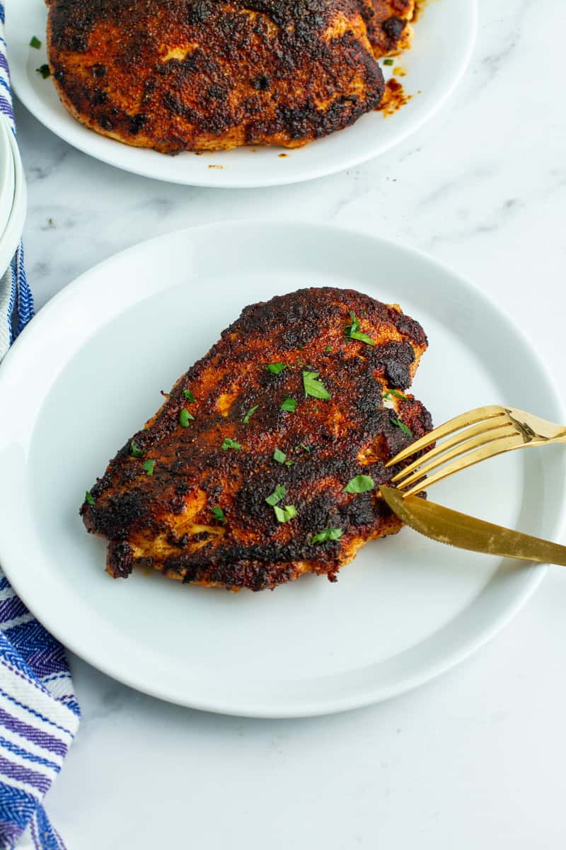 blackened chicken on a plate with fork and knife