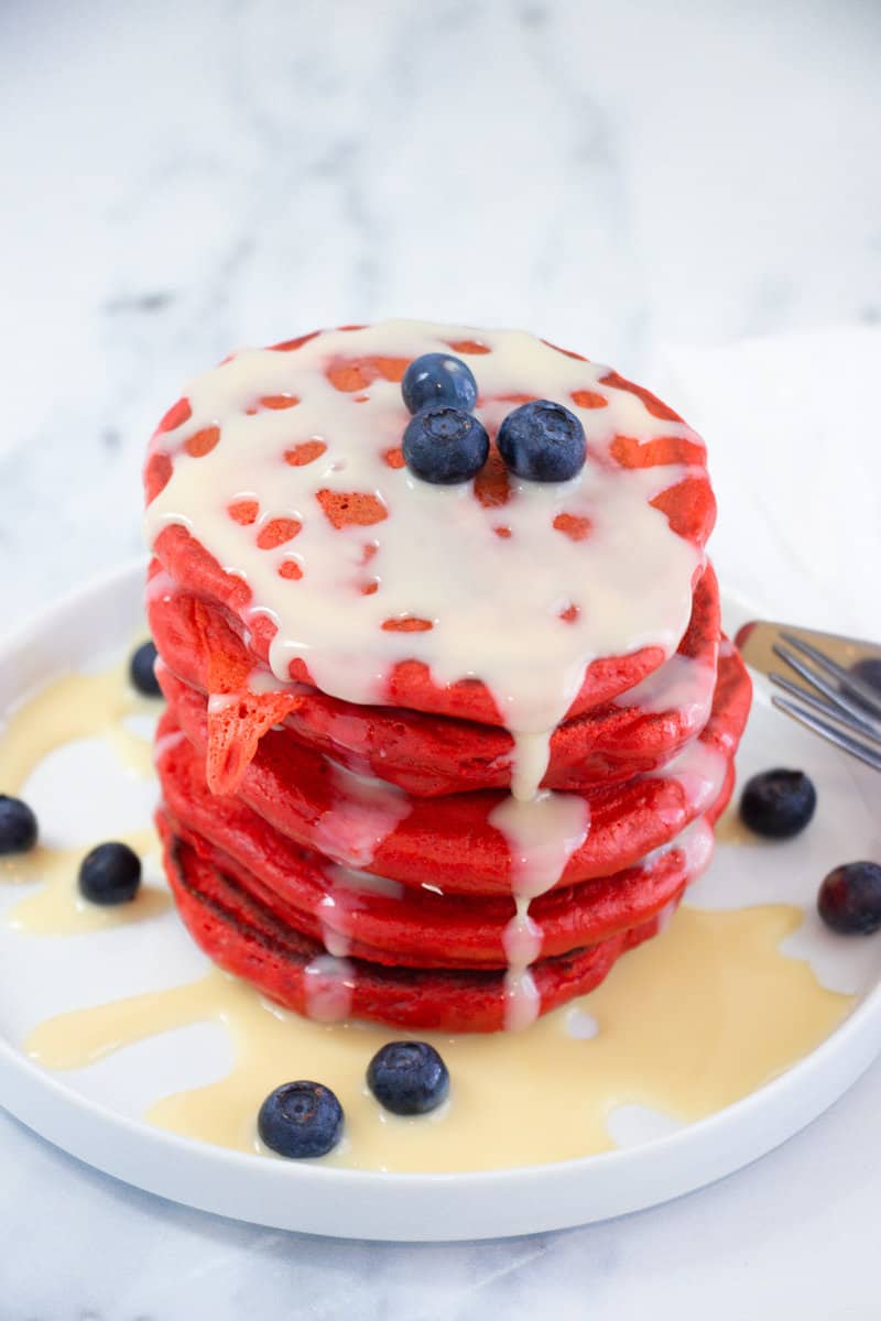 Stack of red velvet pancakes with condensed milk on a plate
