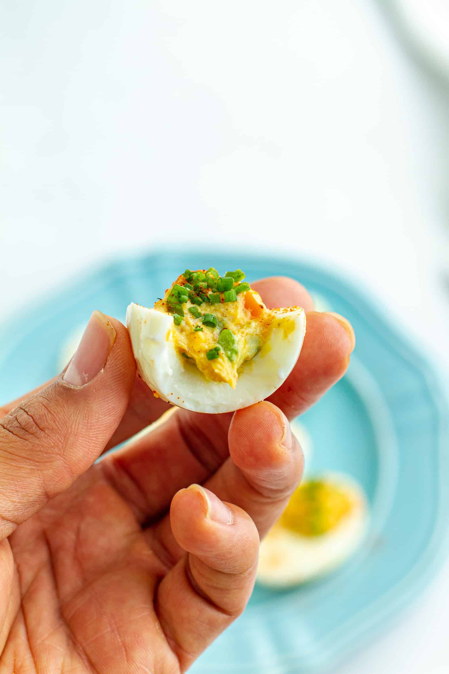 Cajun Deviled Egg with a bite taken out being held in a hand.