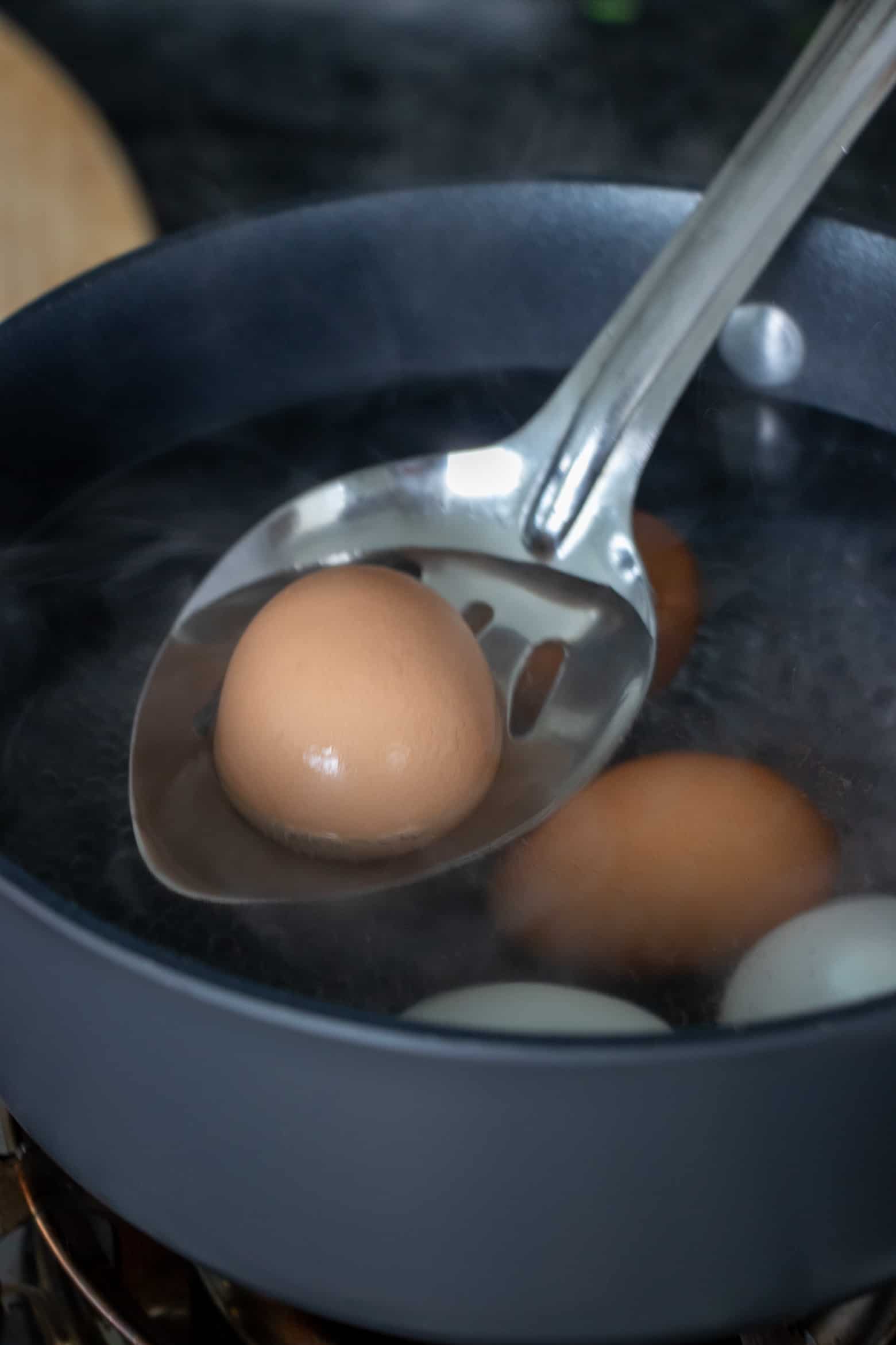 Eggs being added to a pot of boiling water.