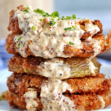 Stack of Fried Green tomatoes with remoulade sauce on a plate.