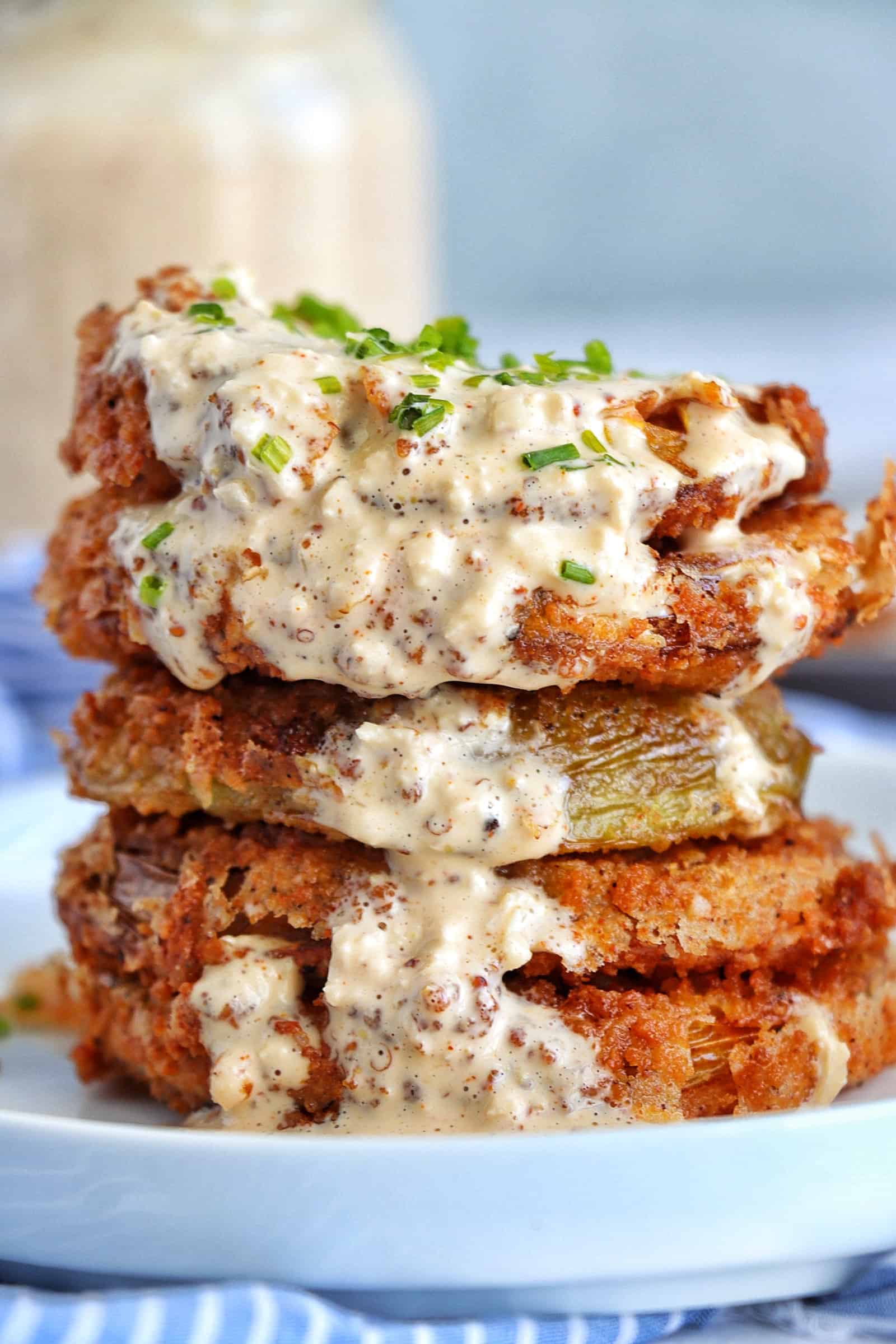 Stack of Fried Green tomatoes with remoulade sauce on a plate.