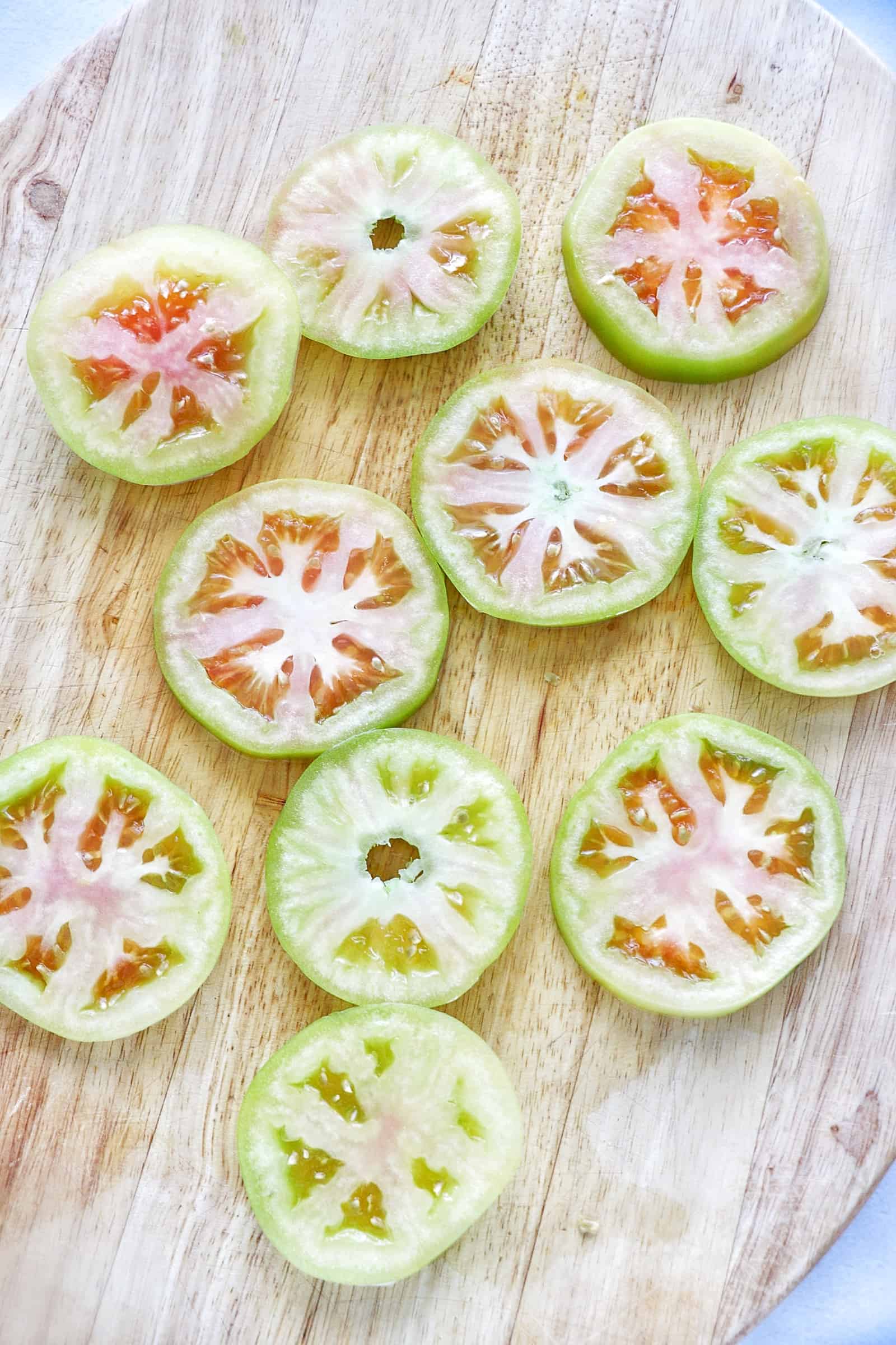 Sliced green tomatoes on a cutting board.