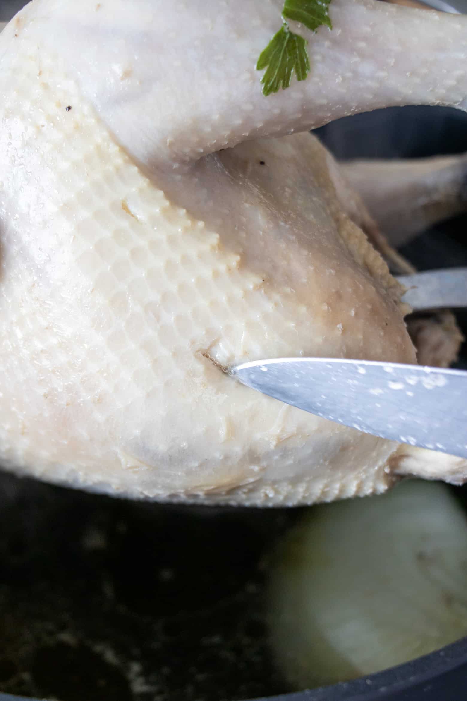Whole cooked chicken juices running clear after being pierced with a knife.