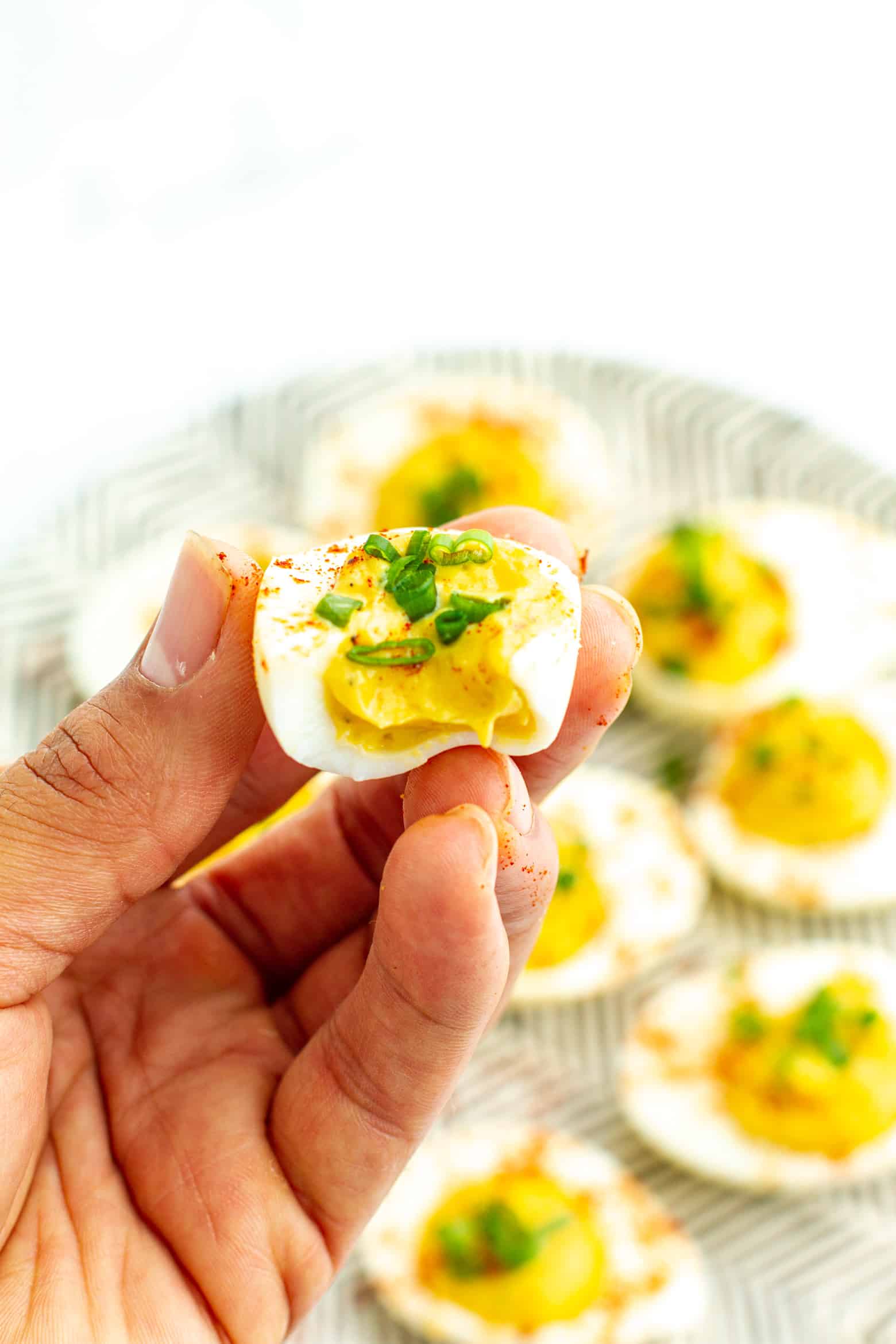 Southern Deviled Eggs  with a bite taken out being held in hand.