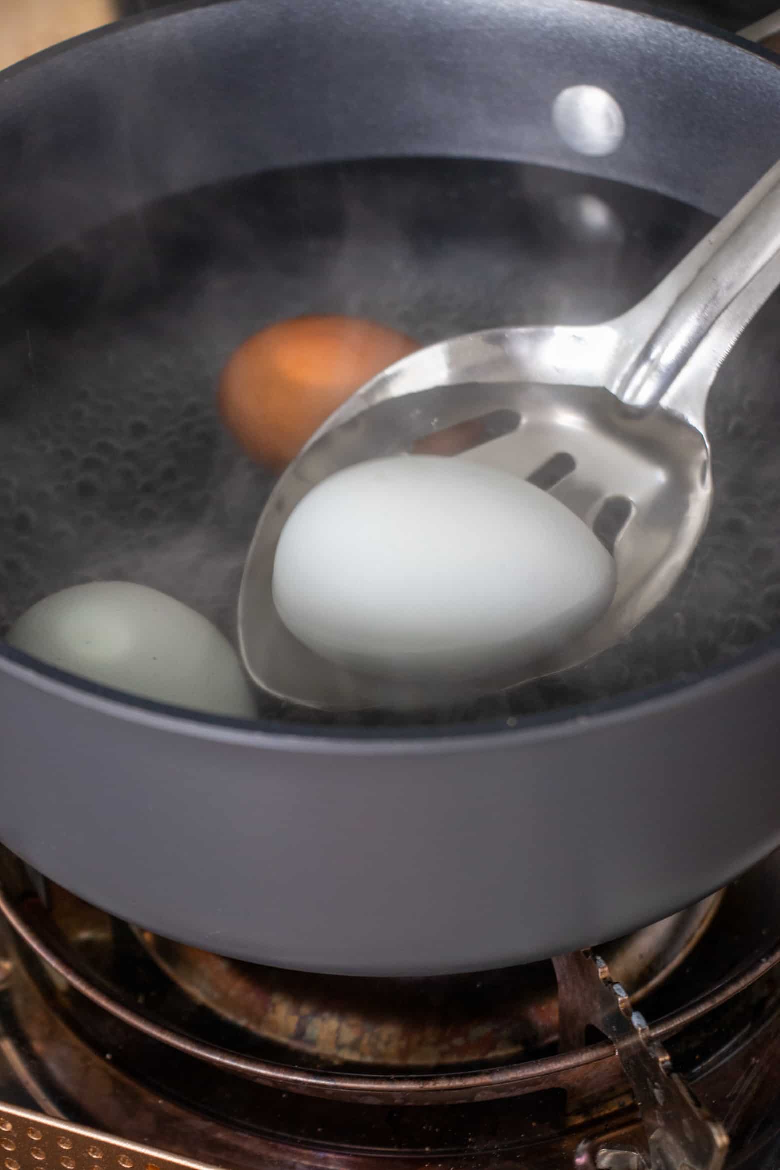 Eggs being added to a pot of boiling water.
