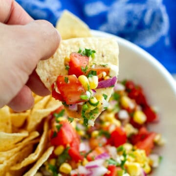 Tomato Corn Salsa on a chip being held.