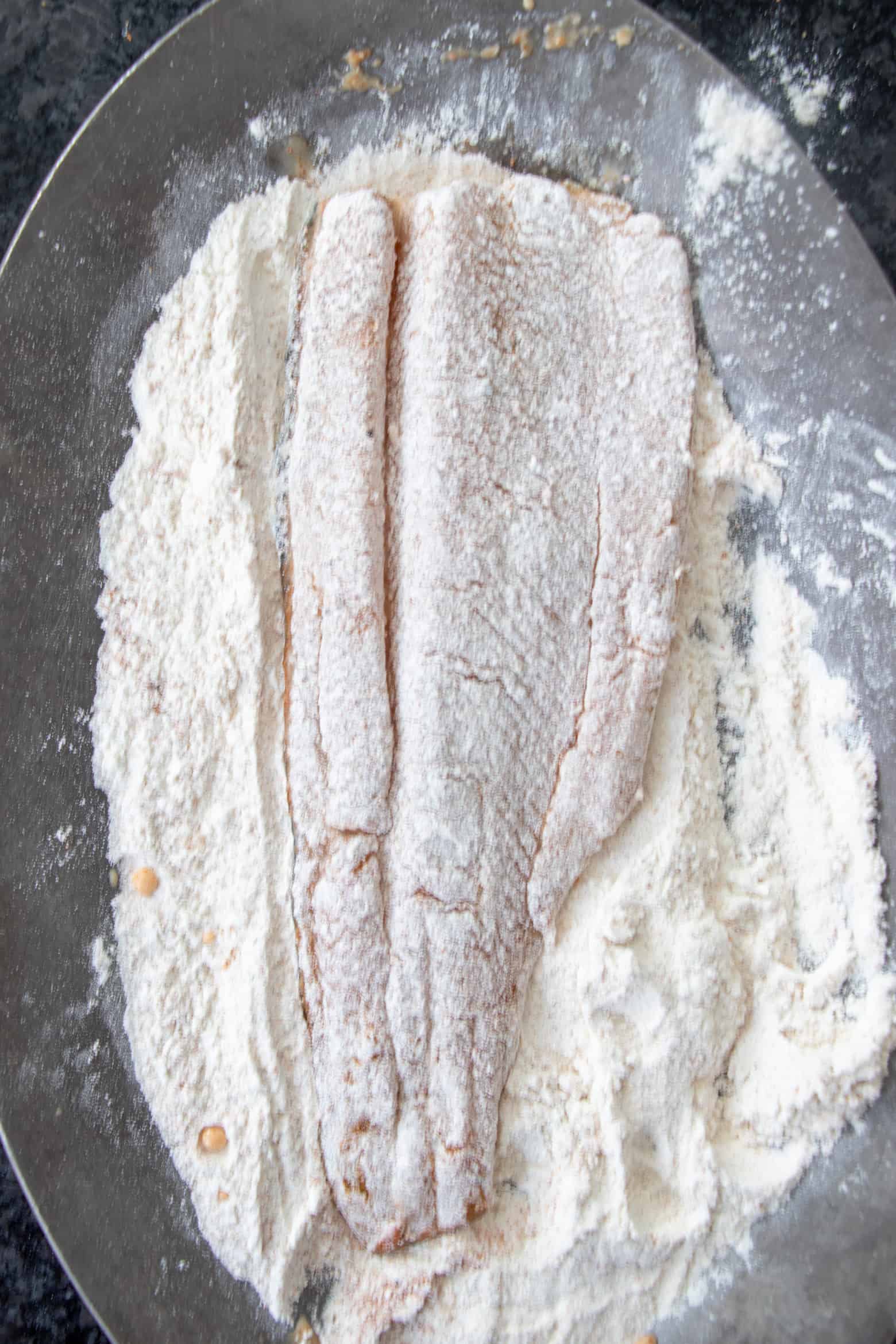 trout lightly dredged in flour on a plate.