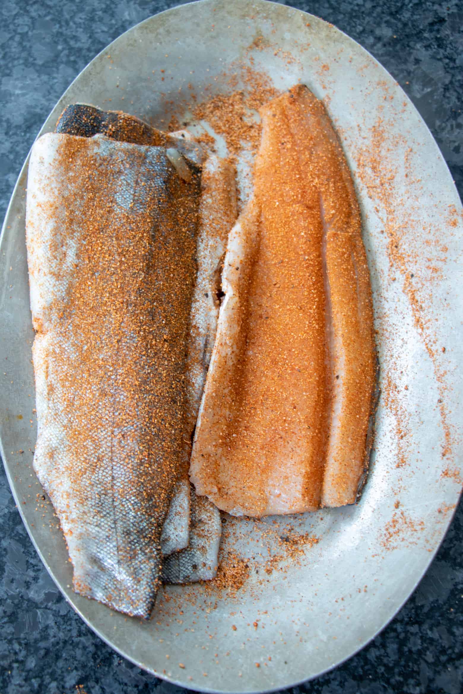 Seasoned trout fillets on a plate.