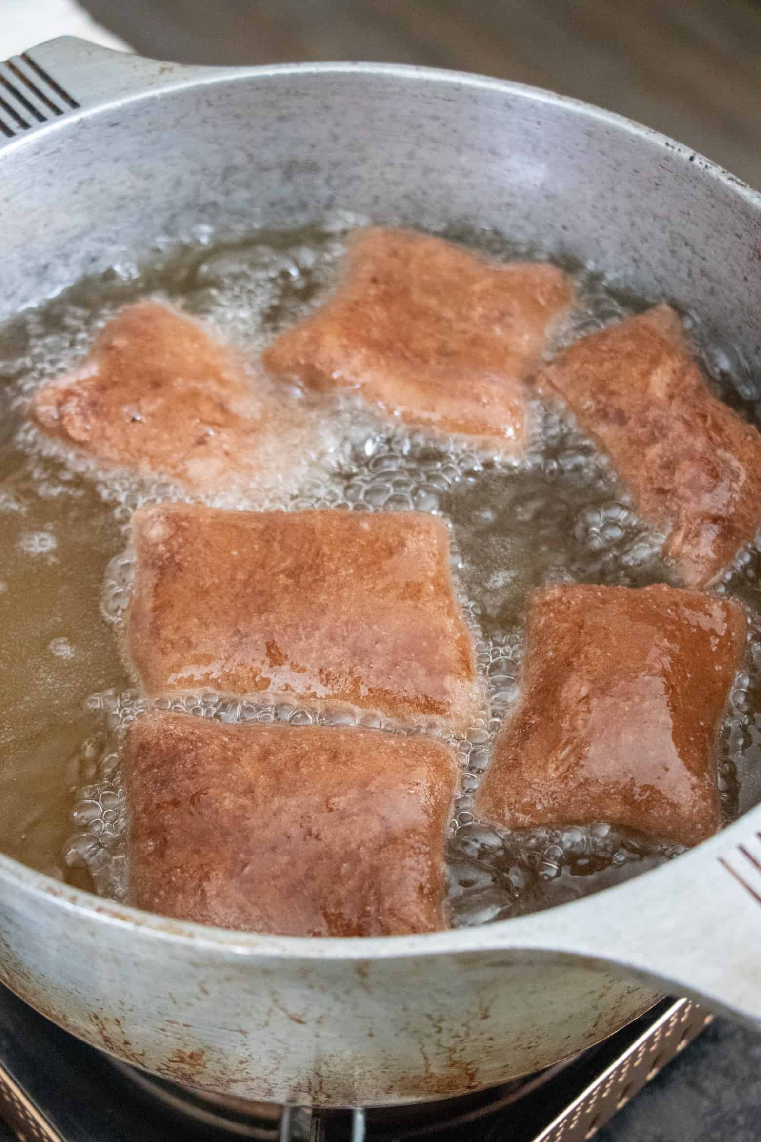 beignets frying in a pot of oil