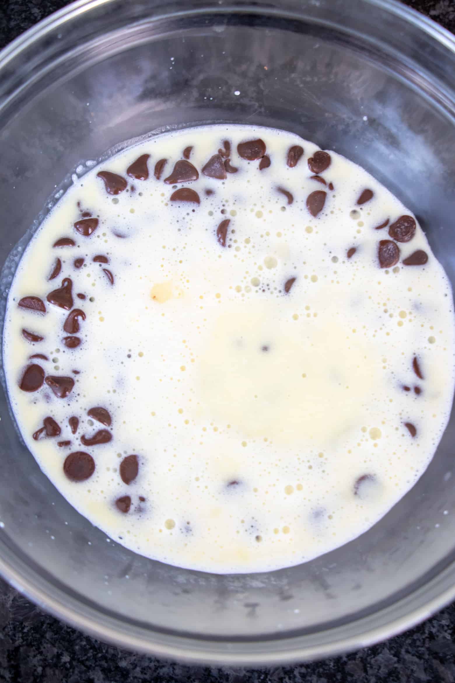 hot heavy cream poured over a bowl of chocolate chips.