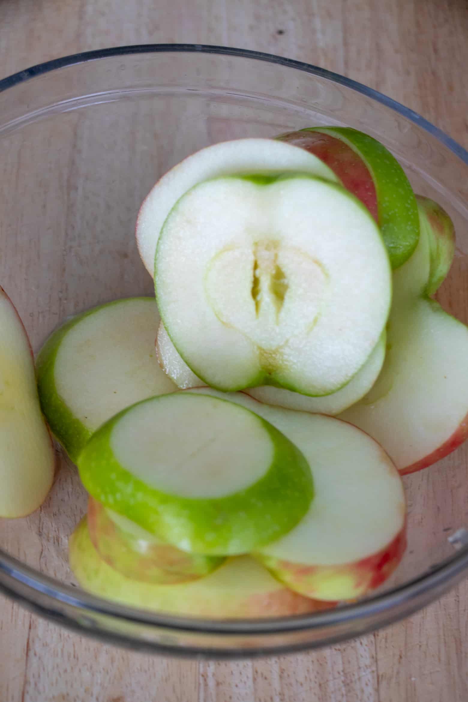 Sliced apples in a bowl covered with lemon juice.