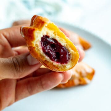 Cherry Fried Pie with a bite taken out being held in a hand.
