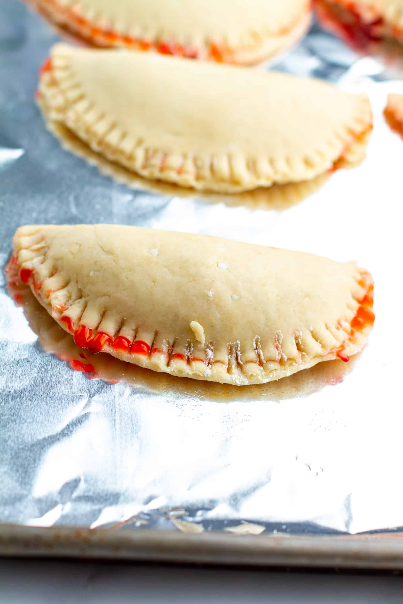 Raw strawberry hand pies on a baking sheet.