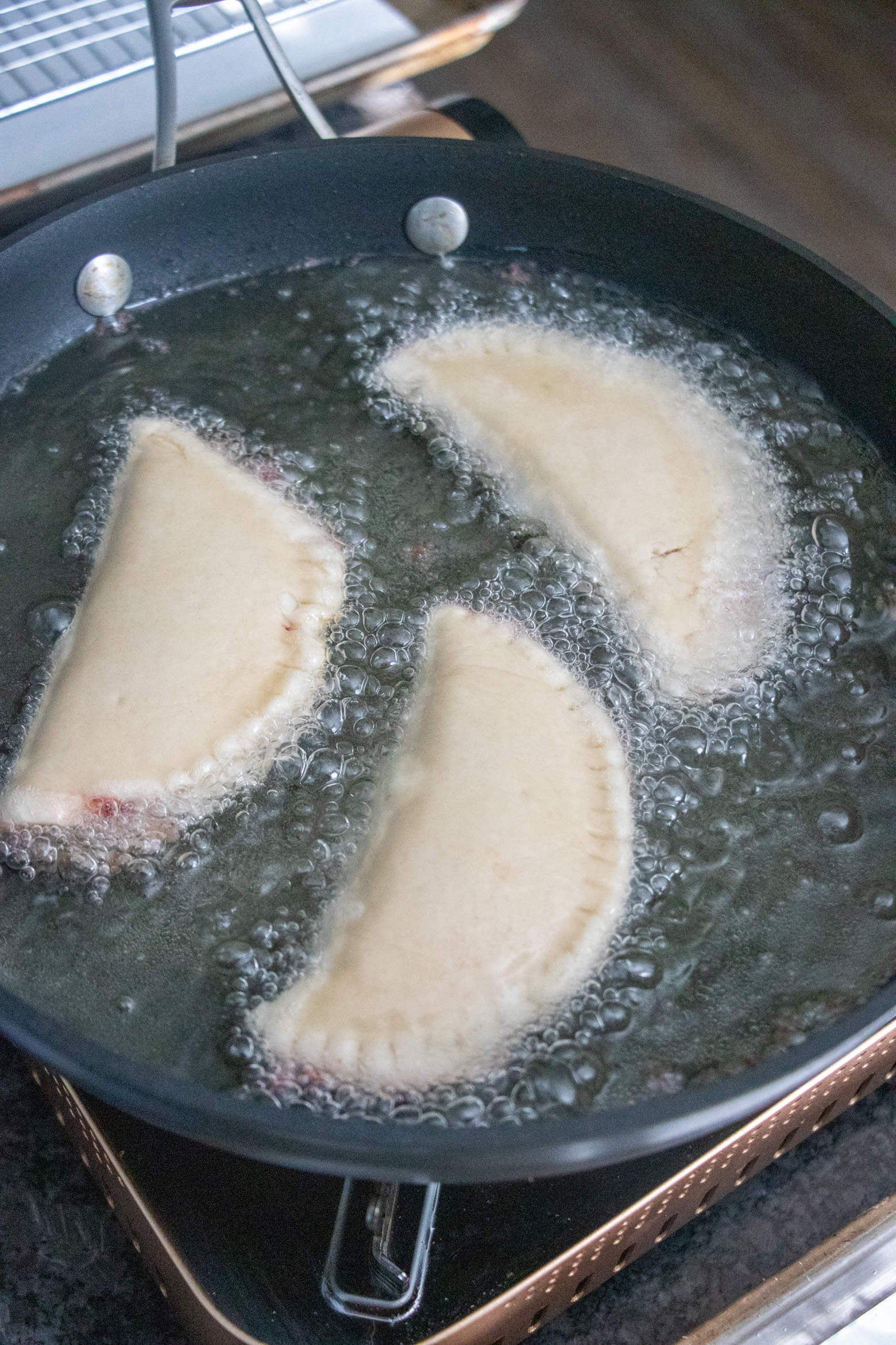 Fried Strawberry Hand Pies frying in oil.