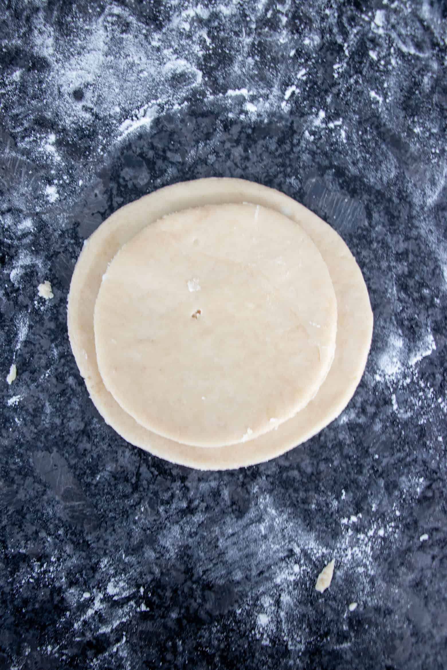 A large pie dough circle and a smaller on top to show the size difference.