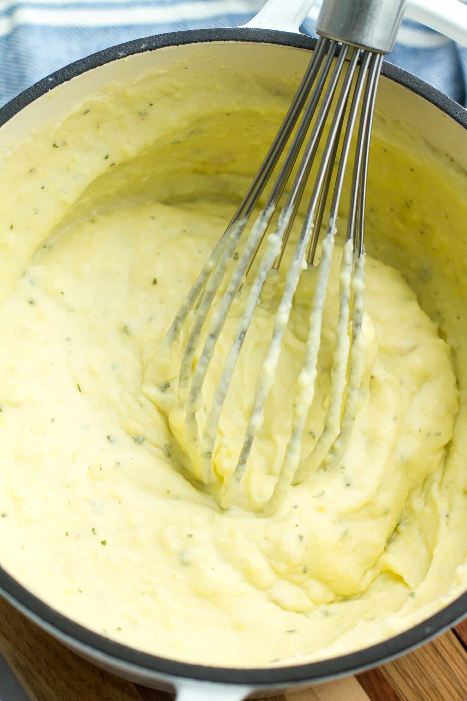 whipped mashed potatoes in pot with whisk