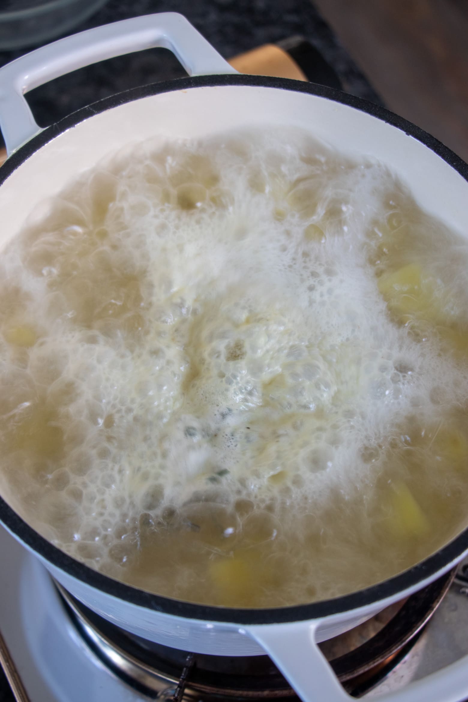 potatoes boiling with foam in pot