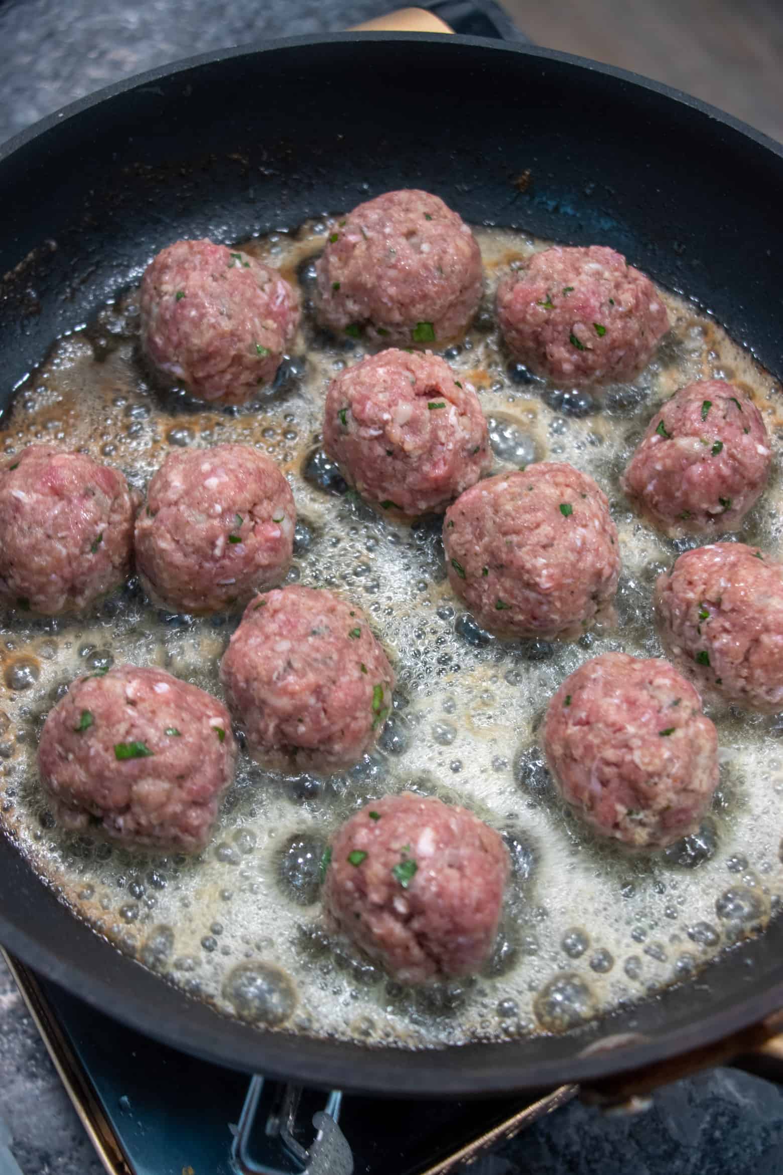 meatballs cooking in a skillet.