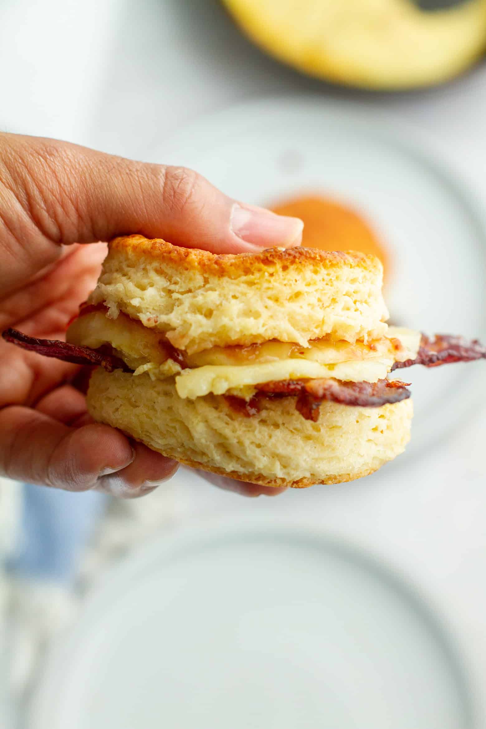 bacon egg and cheese biscuit beginning held in a hand.