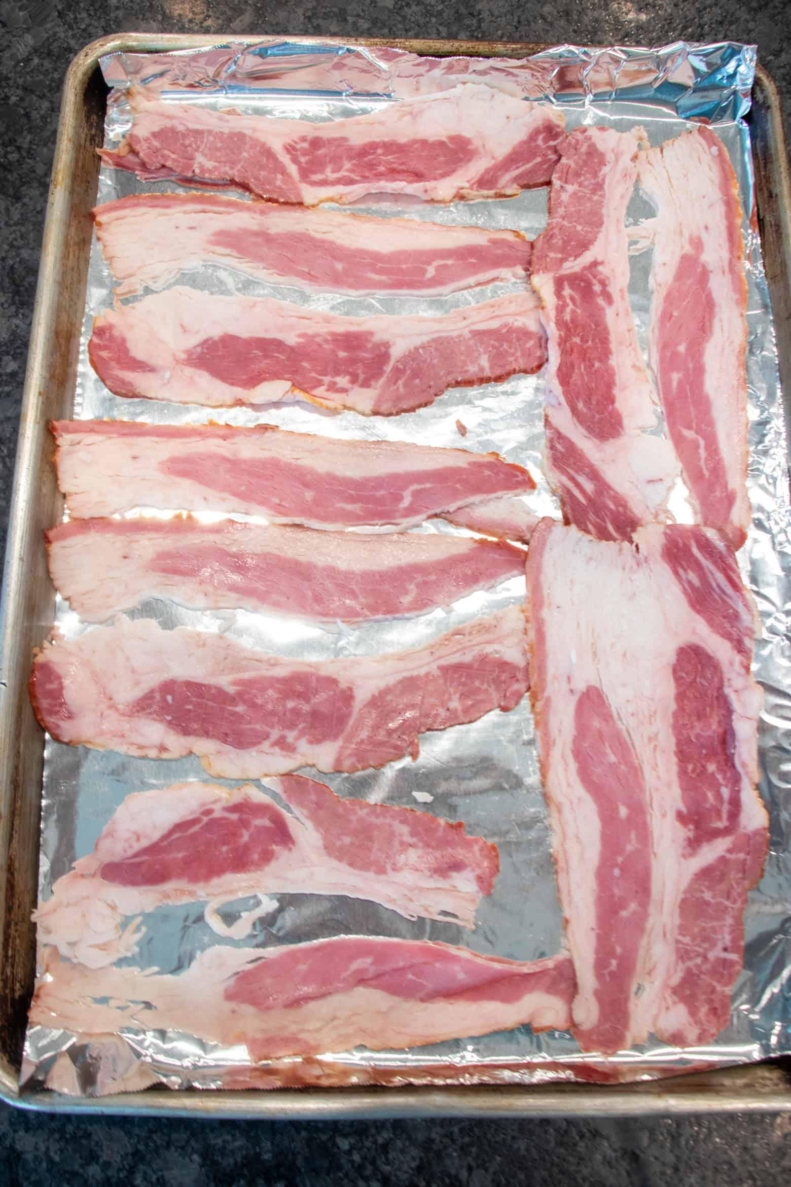 raw beef bacon on a baking sheet.
