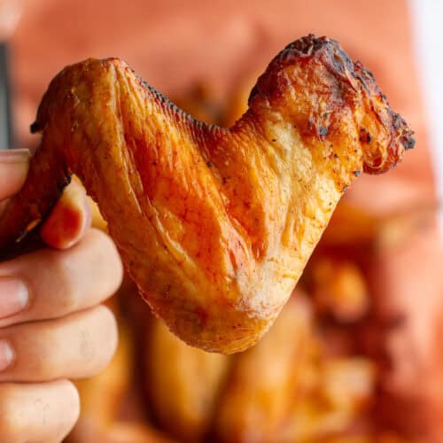 smoked chicken wing being held in hand.