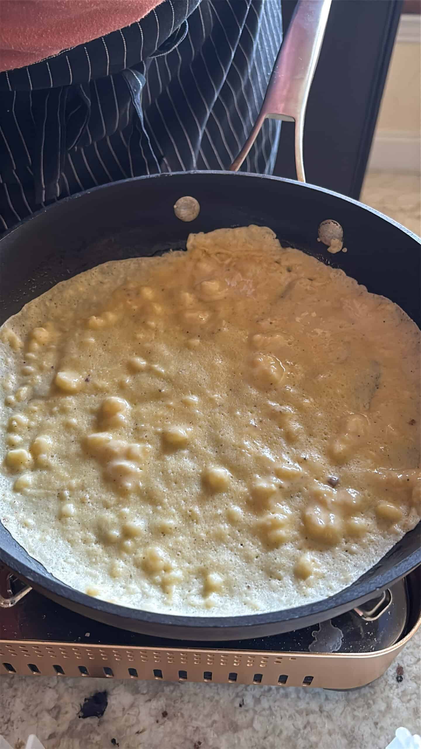 banana crepe batter cooking in a skillet.