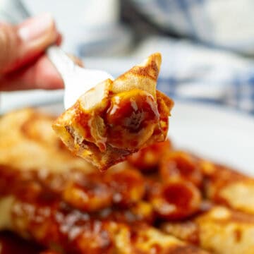 A piece of banana foster crepe on a fork.