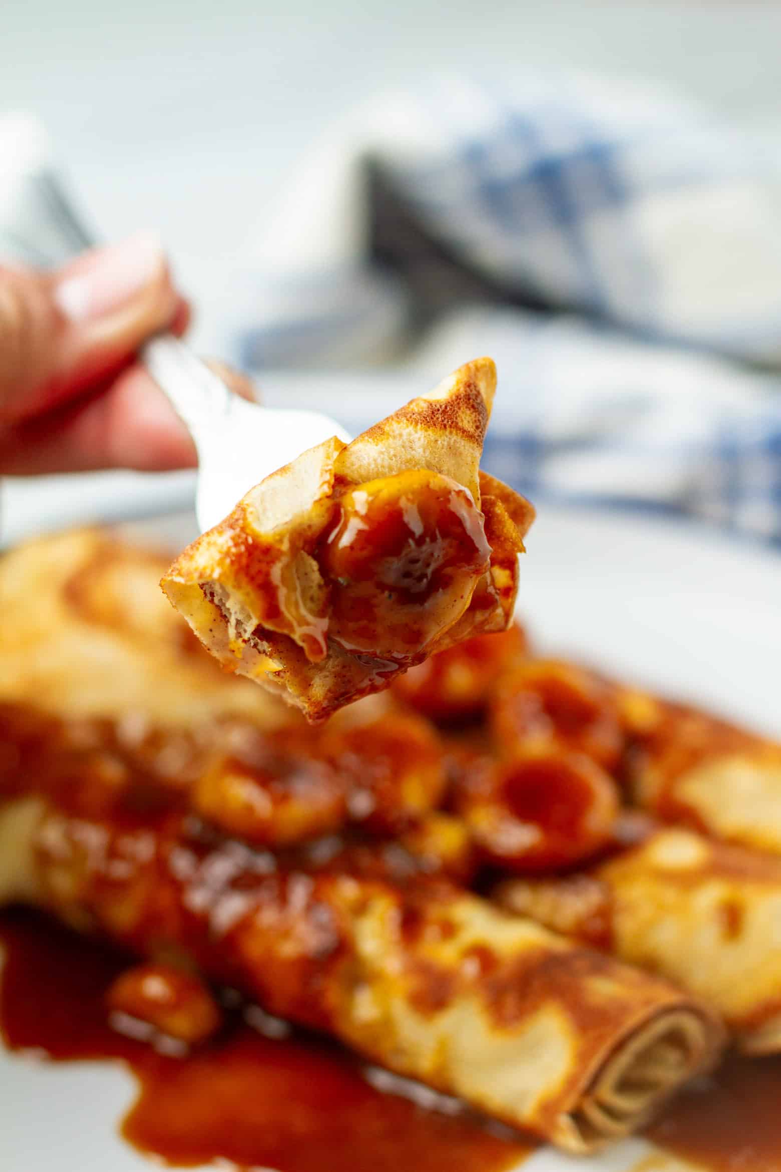 A piece of banana foster crepe on a fork.
