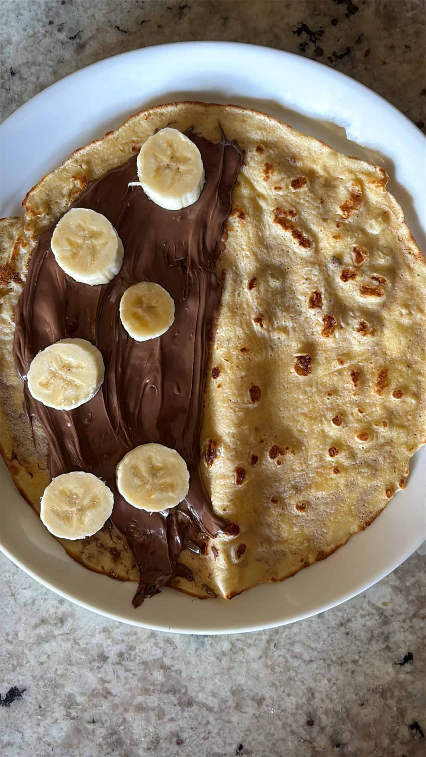 Banana slices and nutella spread on the inside of a crepe.