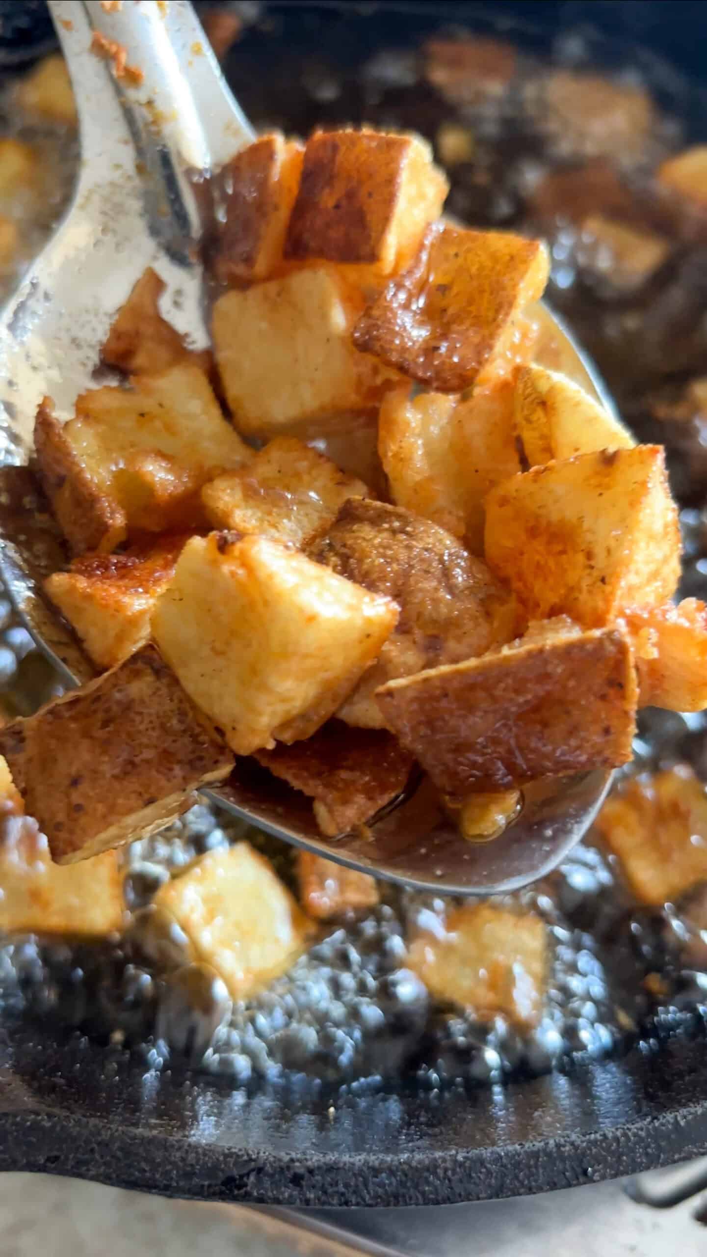 Fried brabant potatoes on a spoon coming out of hot grease.