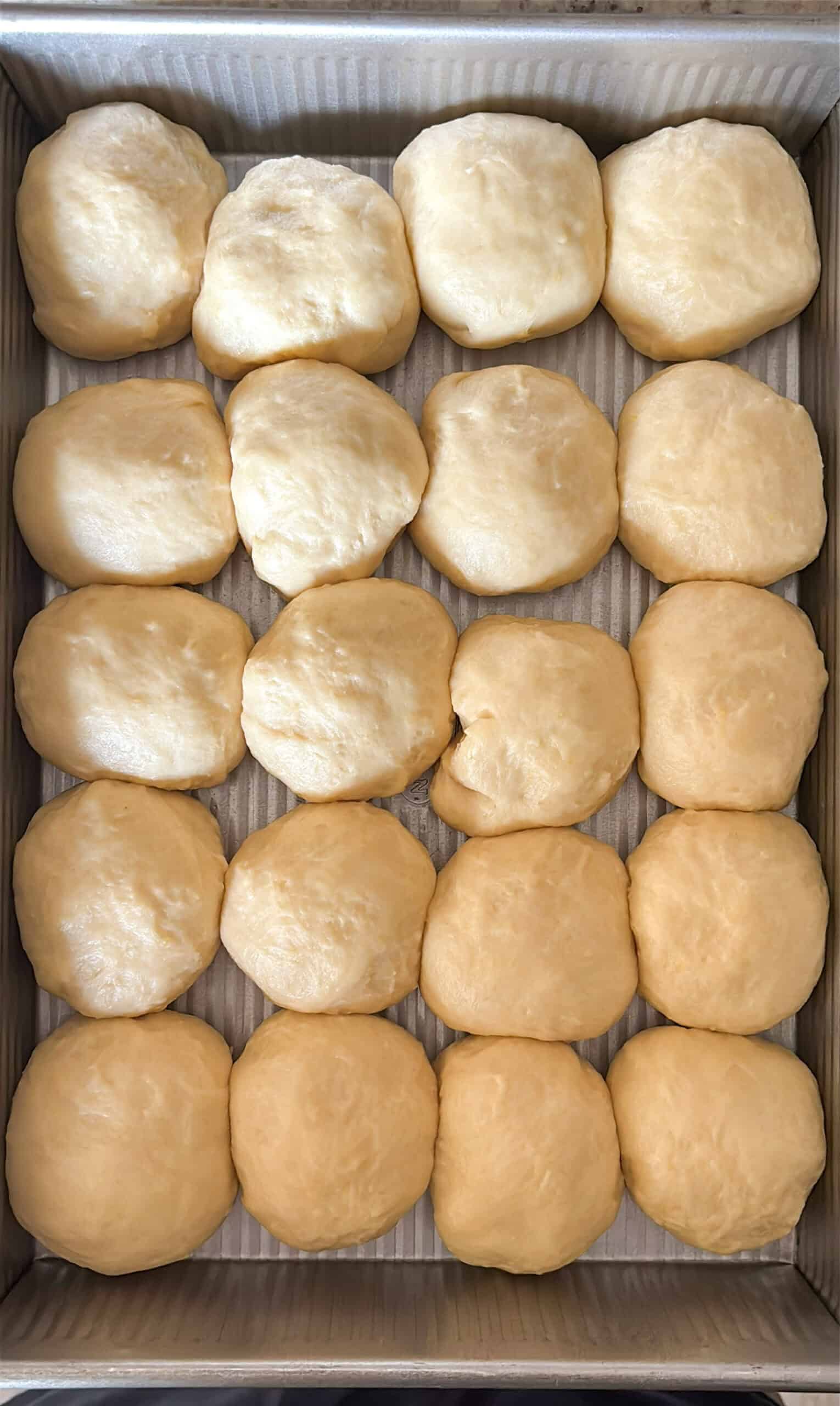 Proofed dough balls in a baking pan.