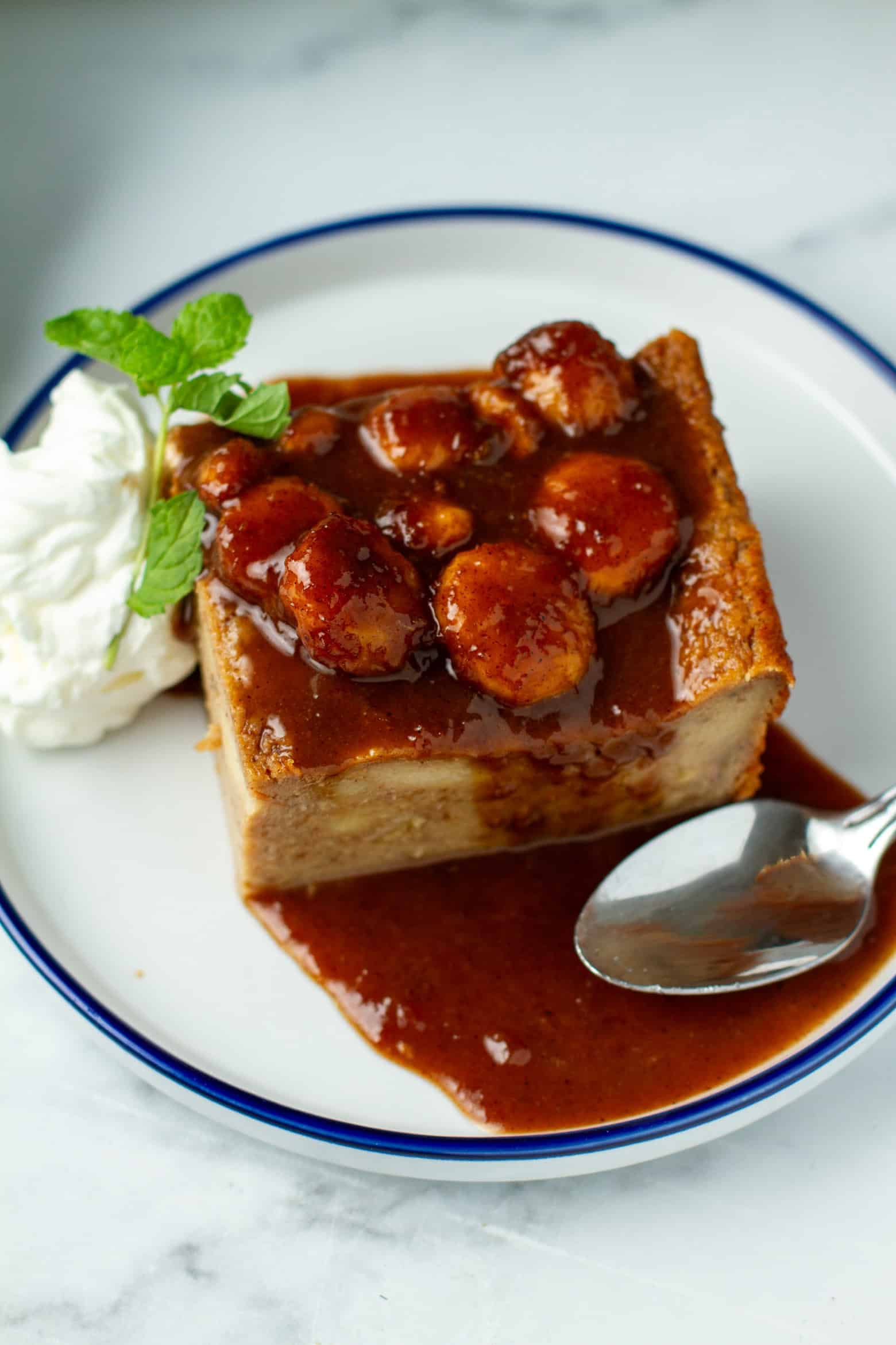 Banana Bread Pudding on a plate with whipped cream and a mint sprig.