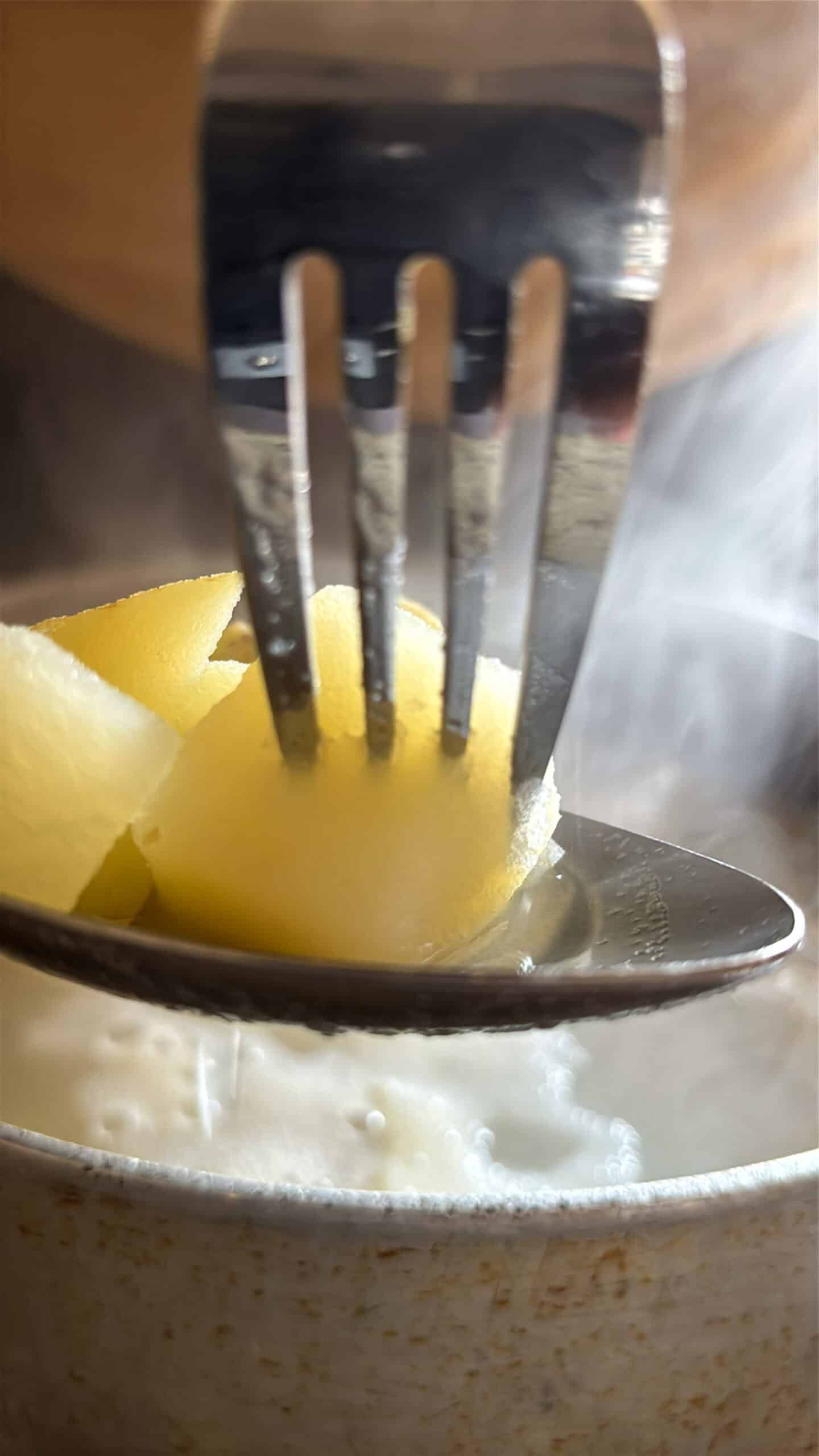A fork tender potato being pierced.