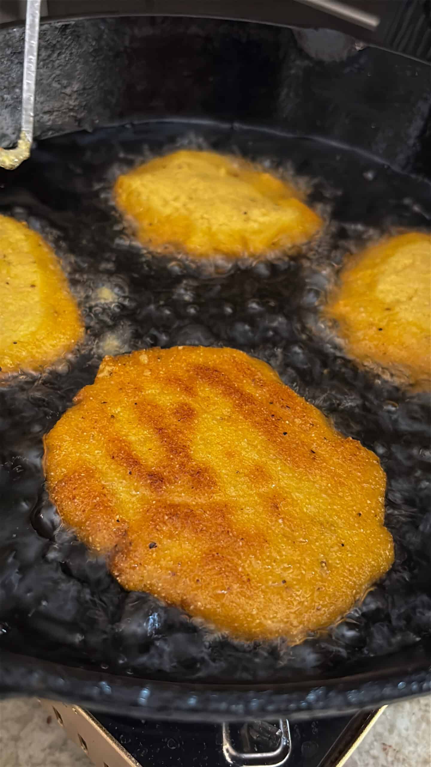 Hot water cornbread frying in a skillet.