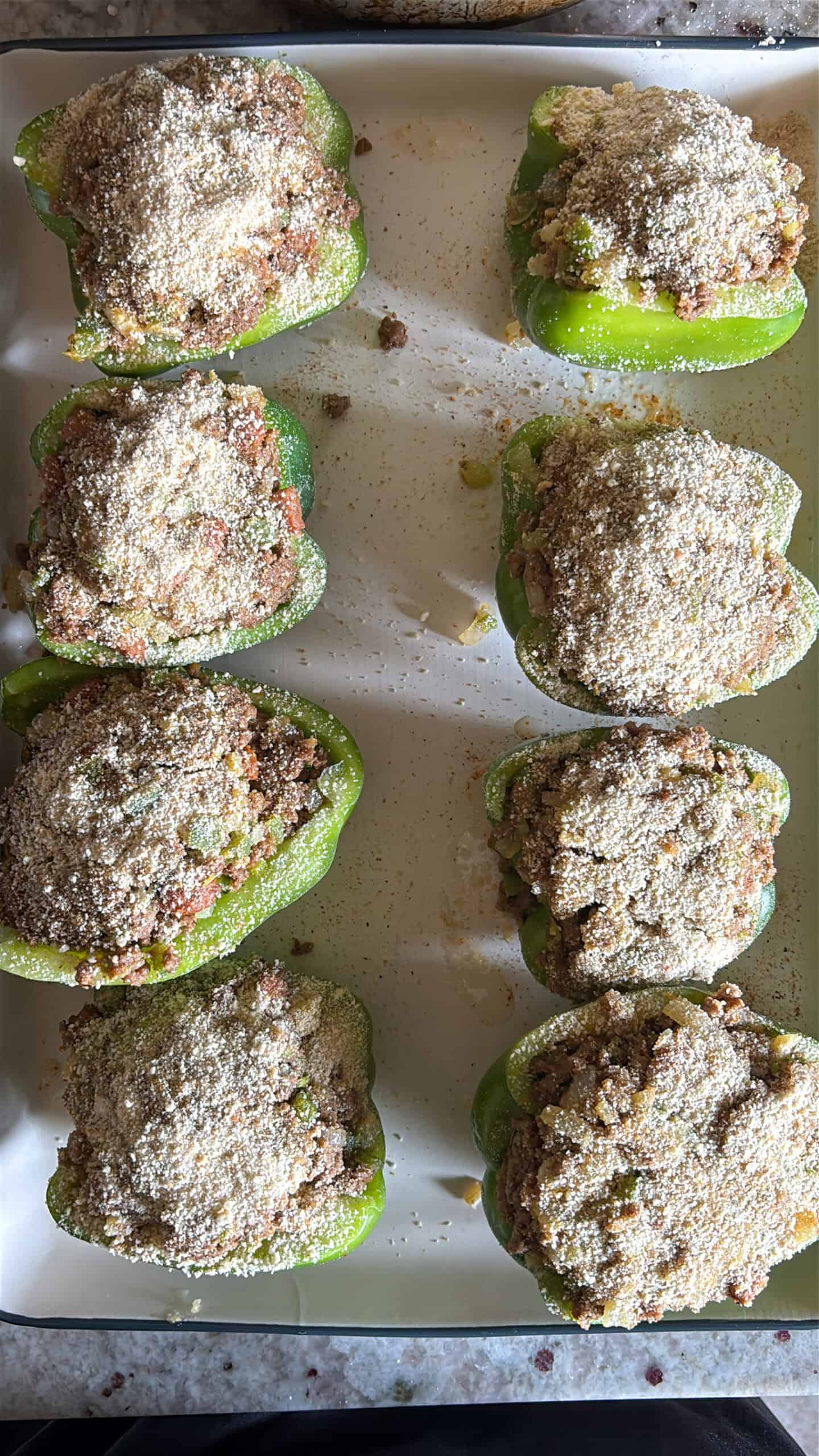 Stuffed bell peppers on a baking sheet before being cooked.