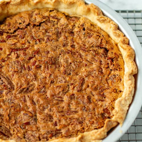 Whole pecan pie on a cooling rack.