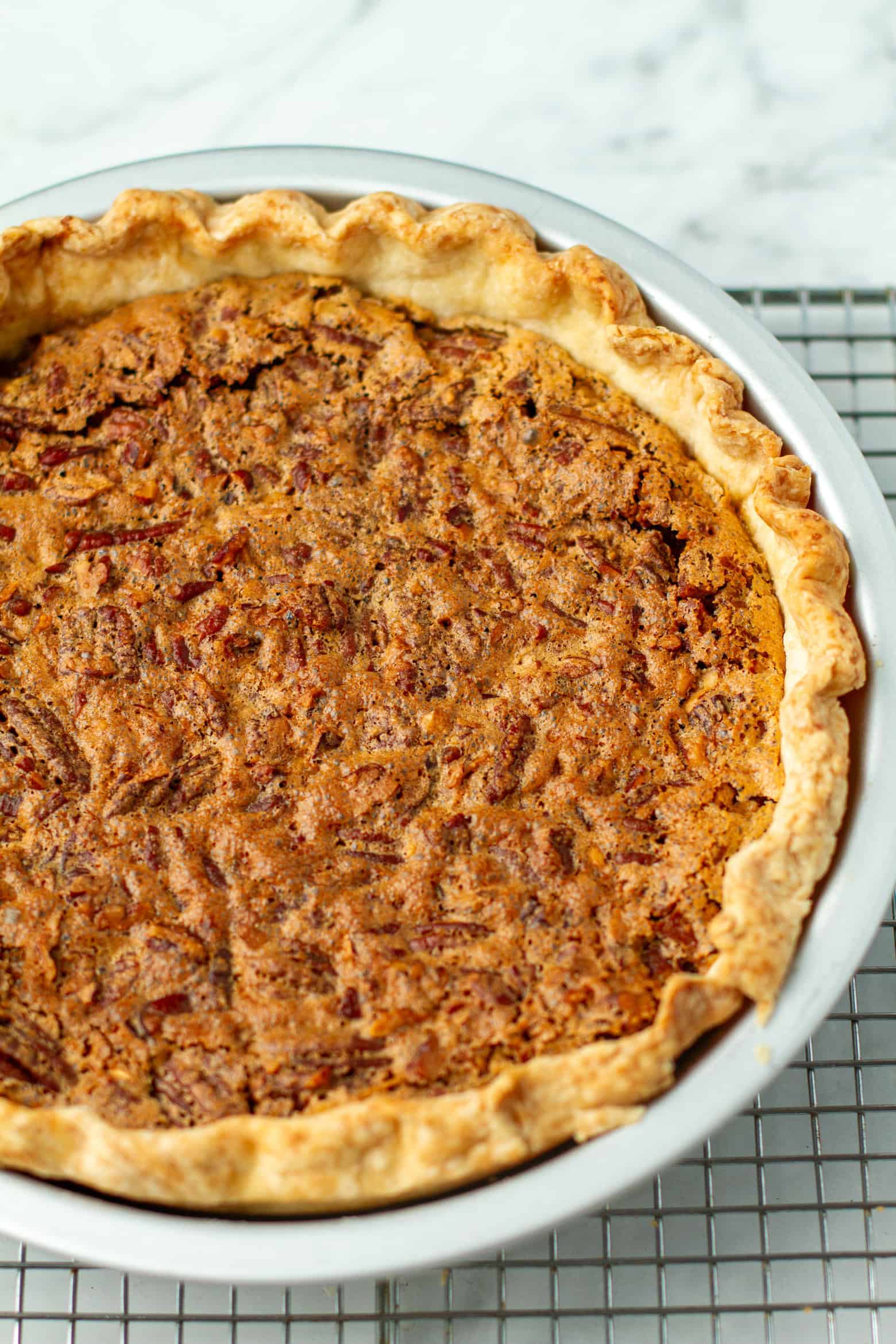 Whole pecan pie on a cooling rack.