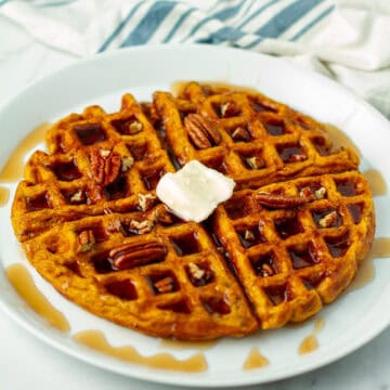 Pecan Waffles with maple syrup and whipped butter on white plate, breakfast, brunch, dessert, syrup, pecans, warm, fluffy, delicious, golden brown, served with a drizzle of syrup, inviting breakfast choice.