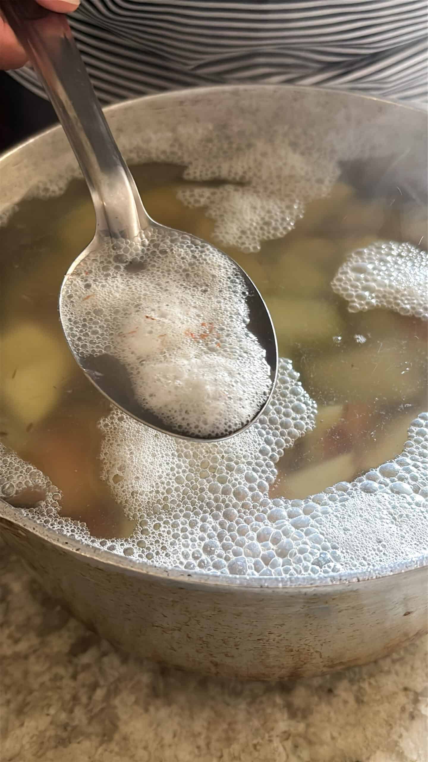 Foam being skimmed away from a potato of boiling potatoes.