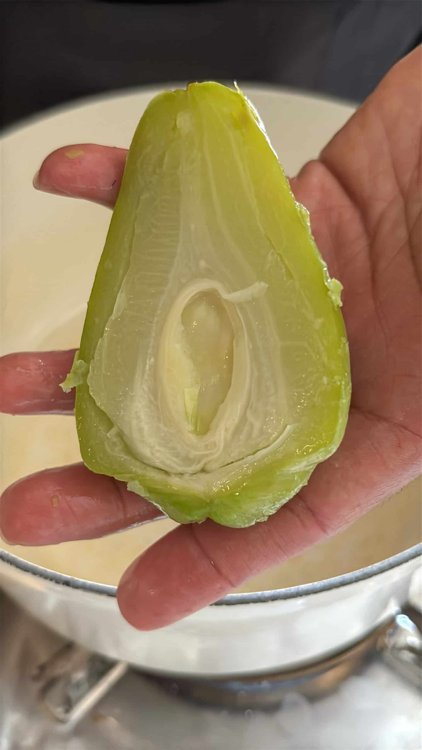 Boiled halved mirliton cut in half showing the seed.