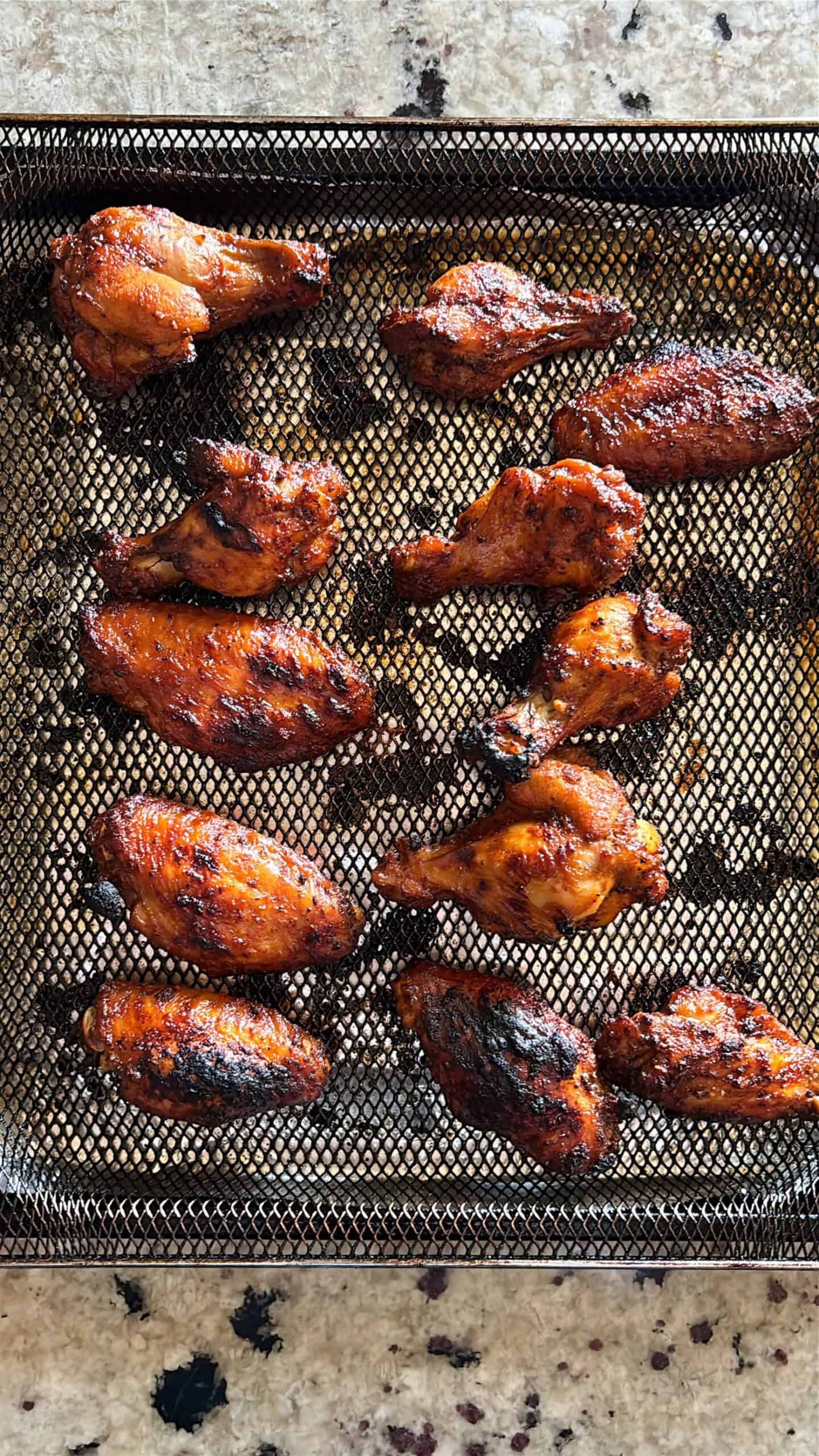 BBQ chicken wings cooked on a air fryer basket.