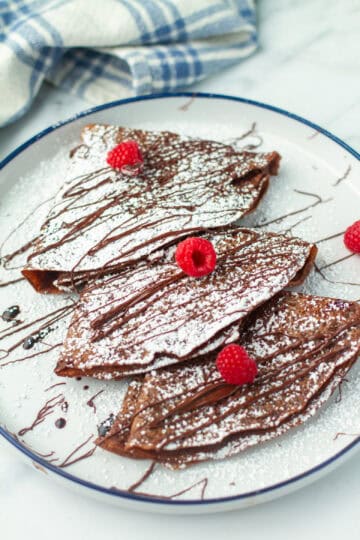 Chocolate Crepes dusted with powdered sugar and chocolate sauce.